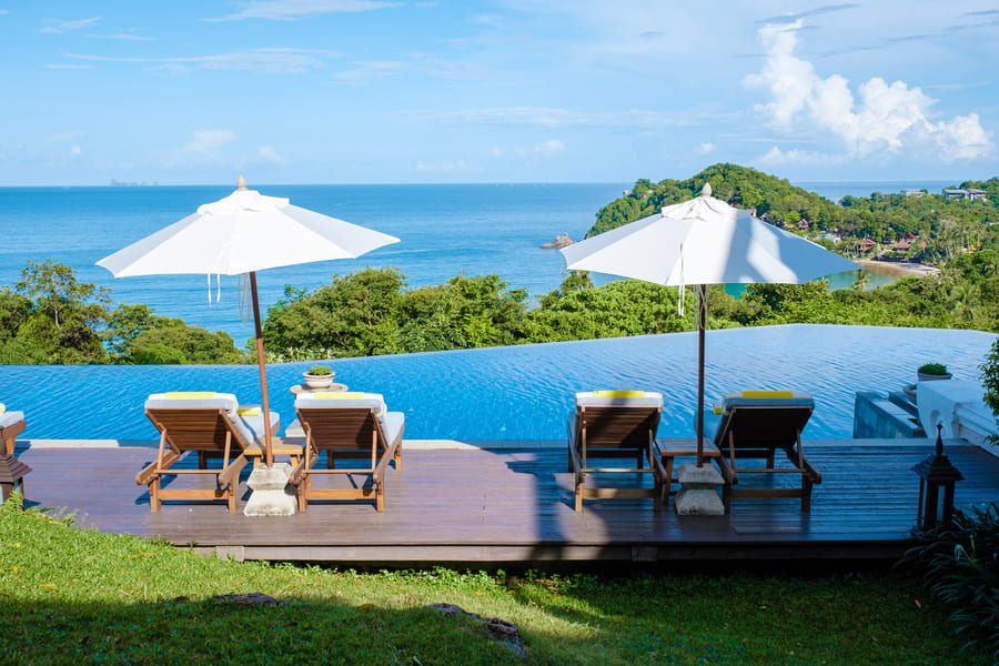 Empty beach chairs facing turquoise waters on a pristine Koh Lanta beach in Thailand, perfect for exclusive luxury relaxation.
