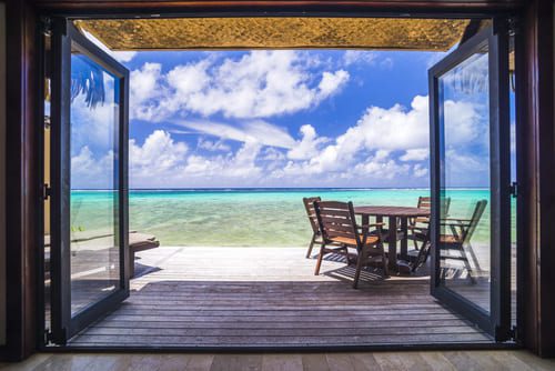 Open-air view from a luxury beachfront villa with outdoor seating and turquoise ocean beyond