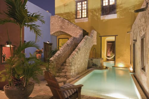 Charming courtyard pool at a boutique luxury hotel in Mexico, featuring rustic stone architecture and colourful walls.