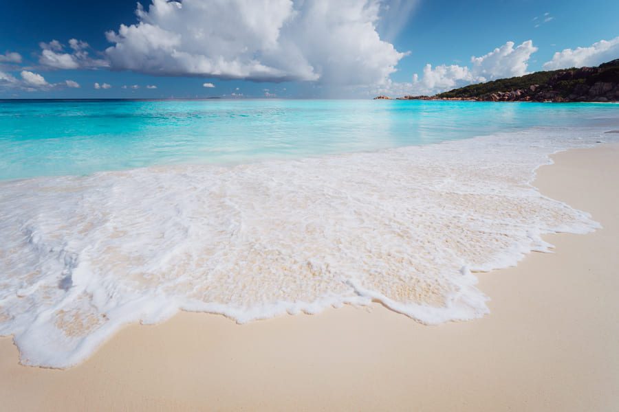 White sand beach with turquoise Caribbean waters and dramatic clouds on the horizon.