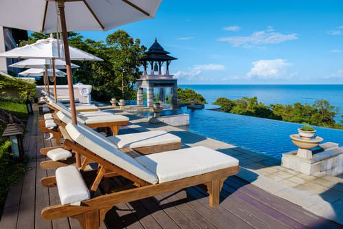 Luxury infinity pool terrace at a five-star resort in Thailand, featuring elegant sun loungers, parasols, and panoramic ocean views.