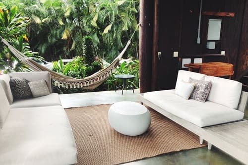 Luxury outdoor lounge area with modern sofas and a hammock surrounded by lush tropical jungle in Mexico.