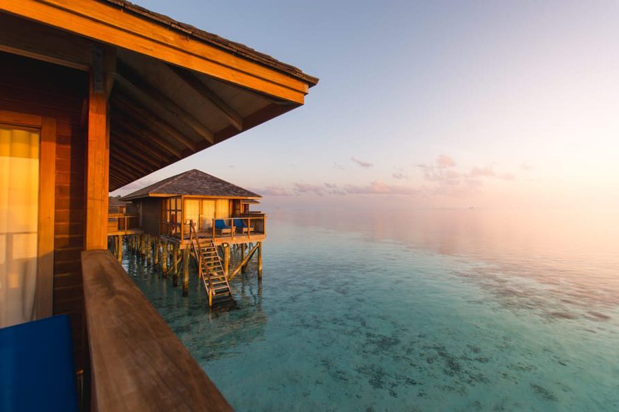 Luxury overwater villas in the Maldives at sunset, with calm turquoise waters and warm golden light reflecting off the ocean.