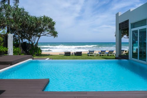 Modern beachfront villa with private pool overlooking the ocean under a bright sky
