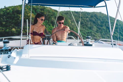 Young couple enjoying a private luxury yacht cruise along the tropical coastline of Mexico, under clear blue skies.