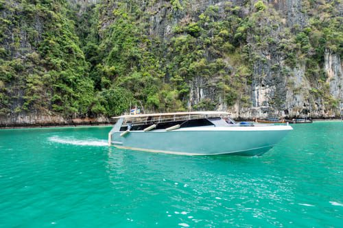 Luxury private speedboat cruising through the emerald waters of Pileh Lagoon, Phi Phi Islands, Thailand.