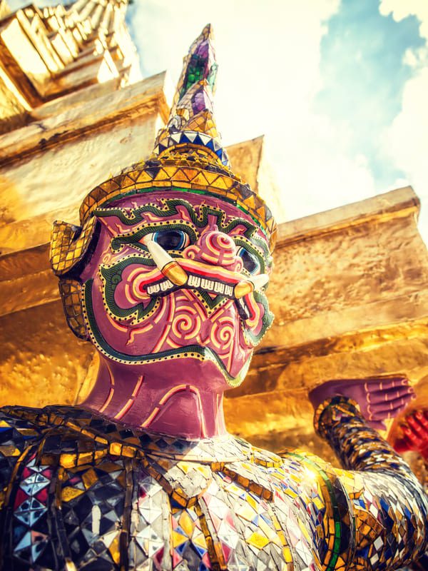 Close-up of a colourful mosaic Yaksha guardian statue at the Grand Palace in Bangkok, Thailand.